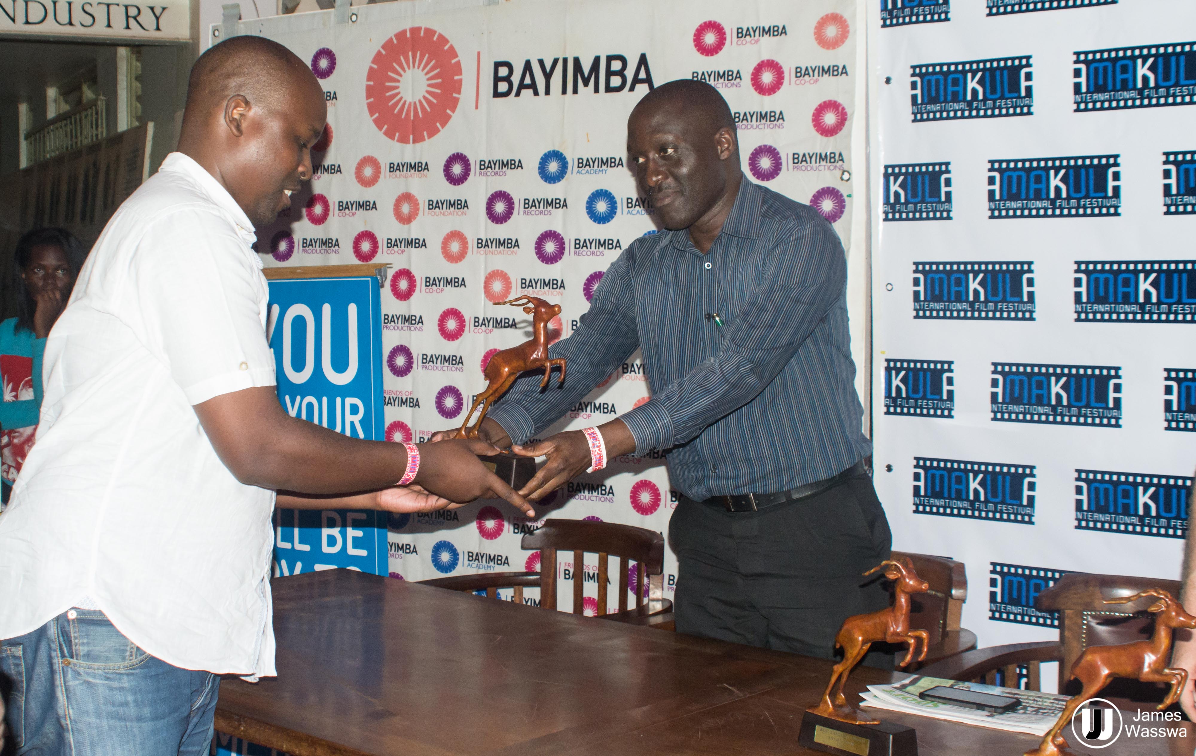 Tanzanian filmmaker Hamadi Mwapachu (L) receiving his Best Feature award from jury member Moses Serugo